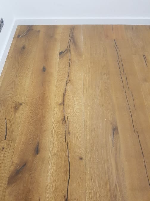 Lamas de madera con veta marcada junto a un rodapié blanco